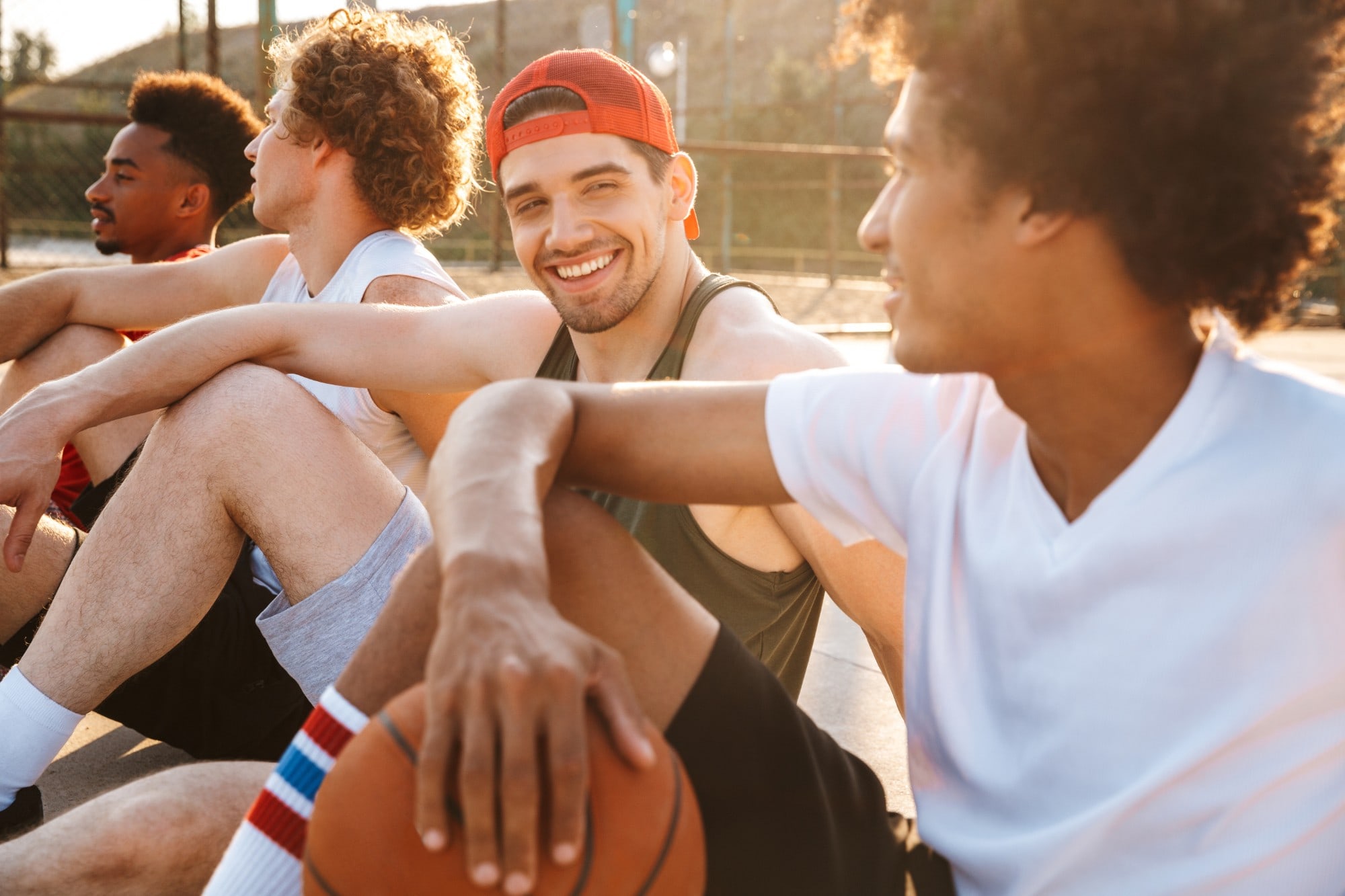 Group of smiling young men relaxing on an outdoor basketball court, celebrating healthy, confident smiles with Smile Ranch Orthodontics – Kingwood orthodontics for teens and adults